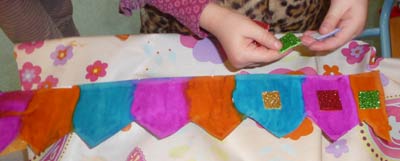 enfant faisant une couronne de plusieurs couleurs avec de l'encre et des carrés pailletés
