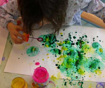 enfant qui souffle des bulles de savon avec de l'encre