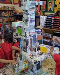 des enfants assemblent des boites de récupération avec des journaux et de la colle à papier peint