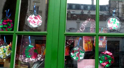 fenêtre avec boules de noel faite avec un disque noir recouvert de papiers déchirés brillants