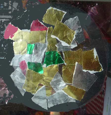 gros plan de la boule de noel faite avec un disque noir recouvert de papiers déchirés brillants