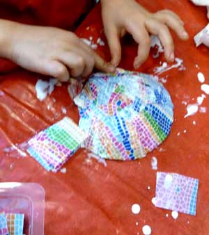 enfant en train de recouvrir une coquille saint Jacques de papier décopatch